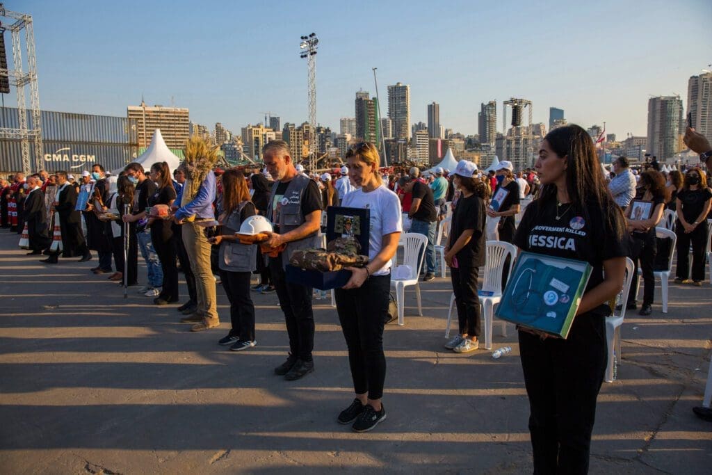 Lebanese hold the portraits and personal effects of their loved ones who died from the Beirut port blast on 4 August 2020, during a memorial Mass.