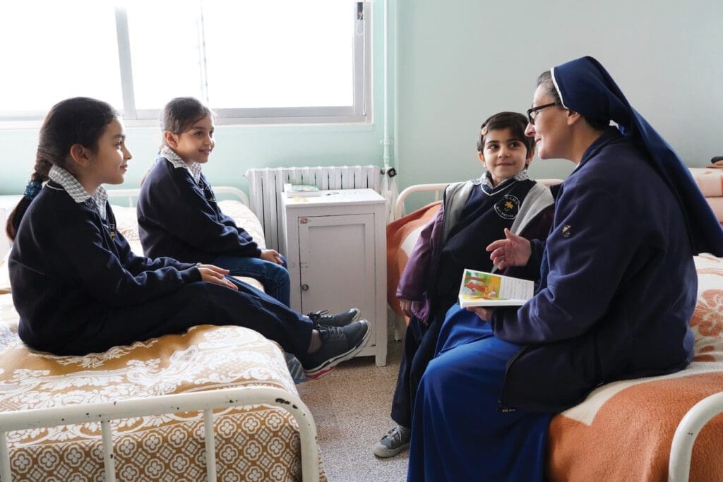 Sister Gladys Sassine reads to three boarders at Blessed Sacrament School in Beit Habbak.