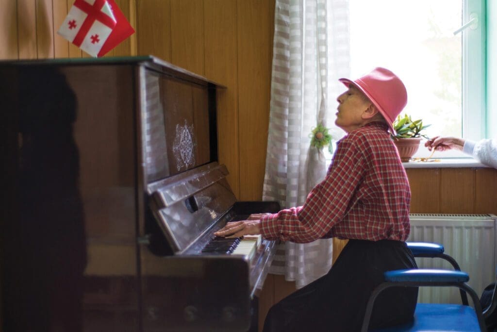 A woman plays piano at a day center with programming for seniors in Tbilisi, Georgia.