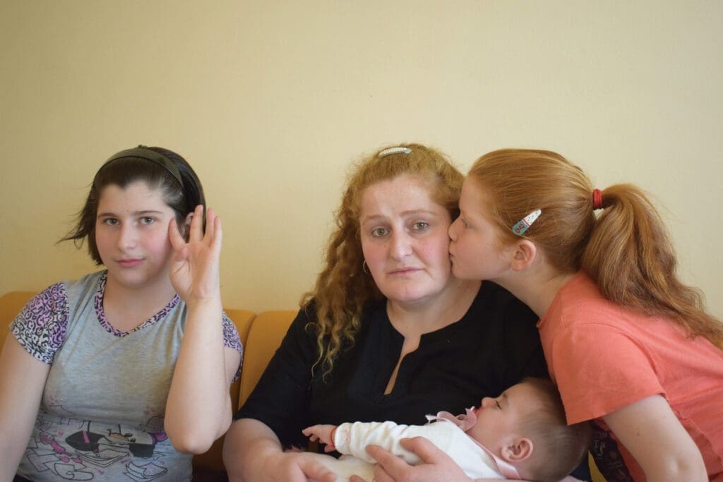 Mother holding a baby and her other two daughters next to her, Tbilisi.