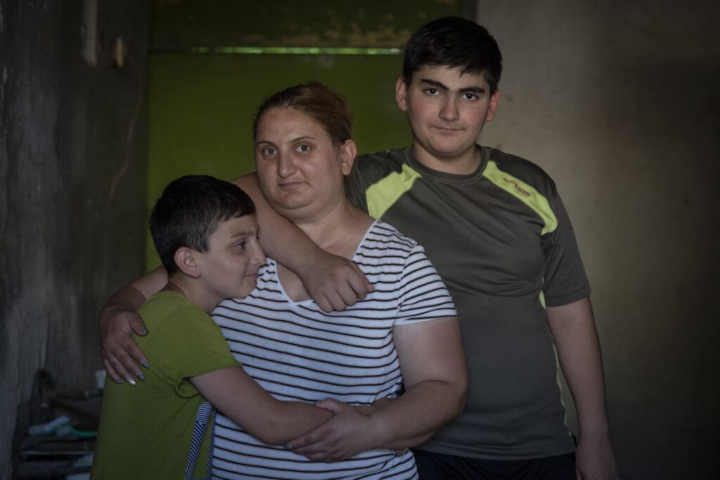 Armenian mother poses with her two sones who are hugging her.