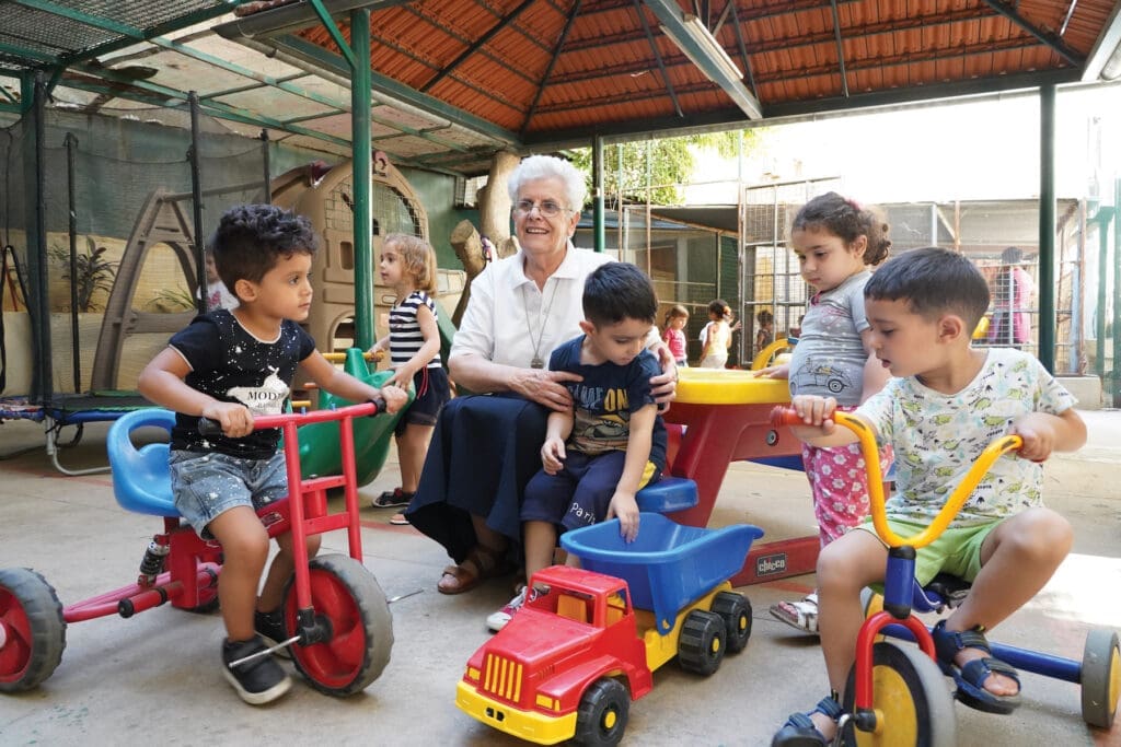 Sister Wardeh Kayrouz, F.M.M., sits with children at a day care playground in Nabaa, Lebanon.