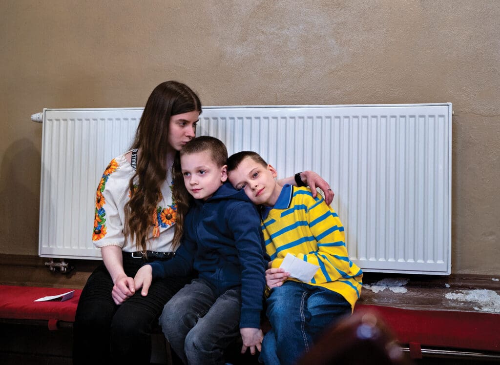 The Leshenka children comfort each other in the Greek Catholic cathedral in Kosice as their mother speaks about how they fled Kyiv.