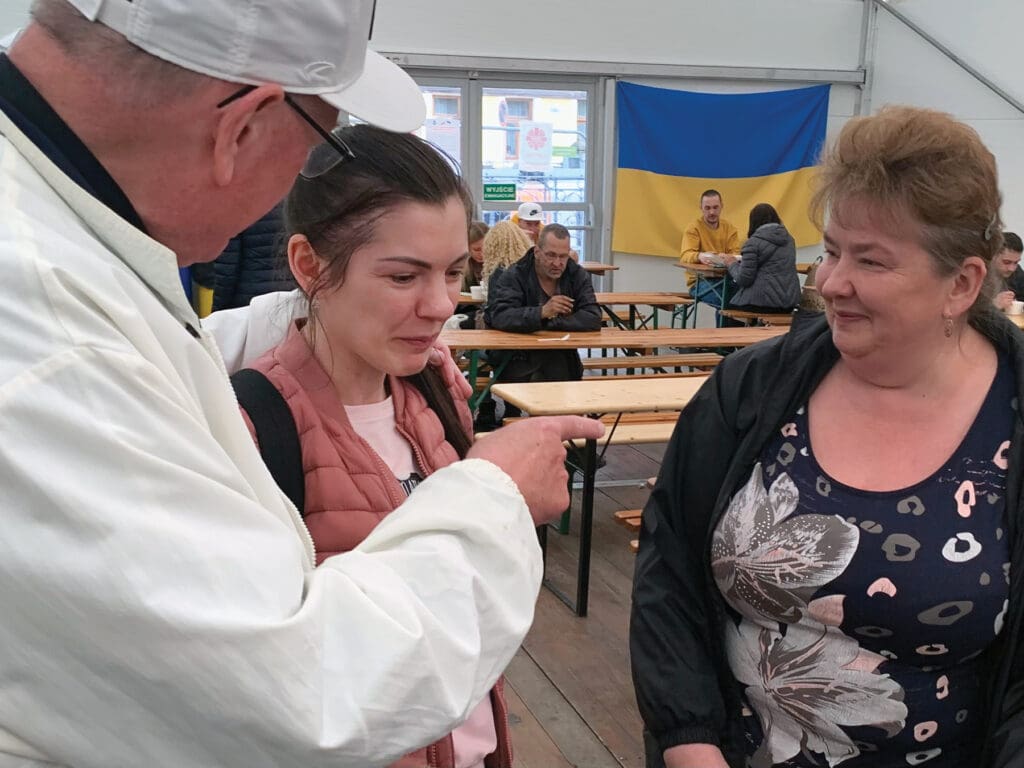 Cardinal Timothy M. Dolan speaks with Ukrainian refugees at a Caritas center in Krakow.