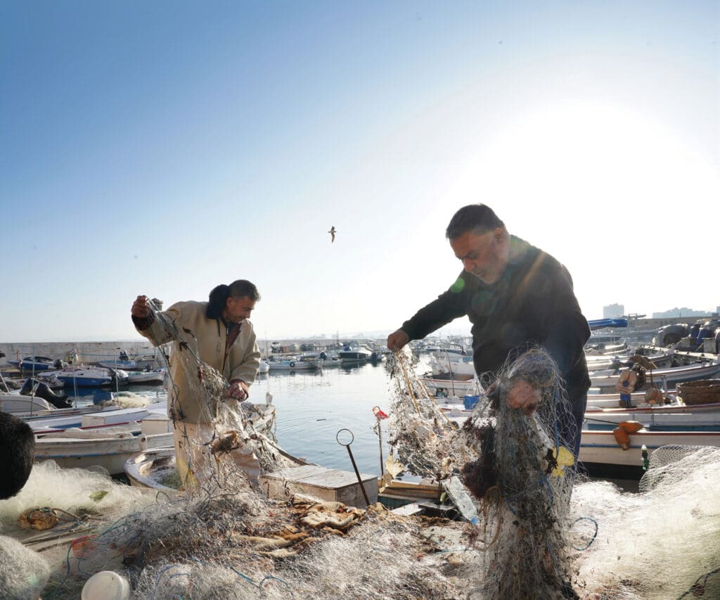 Two fishermen untangling crabbing nets.