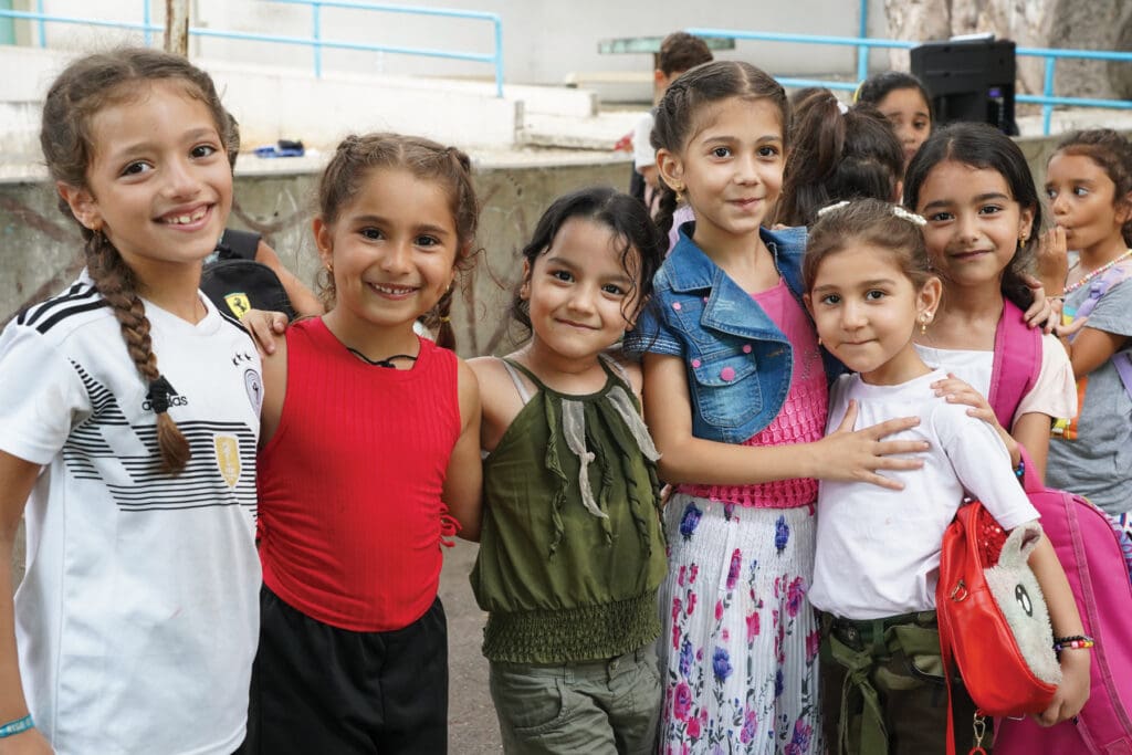 Group of young girls, hugging and smiling at the camera.